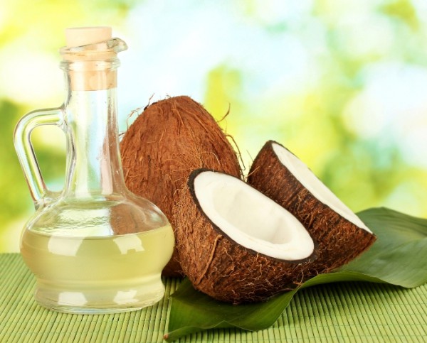 decanter with coconut oil and coconuts on green background